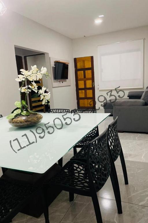 ein Esstisch mit einer Vase mit Blumen darauf in der Unterkunft Bertioga Rio da Praia in Bertioga