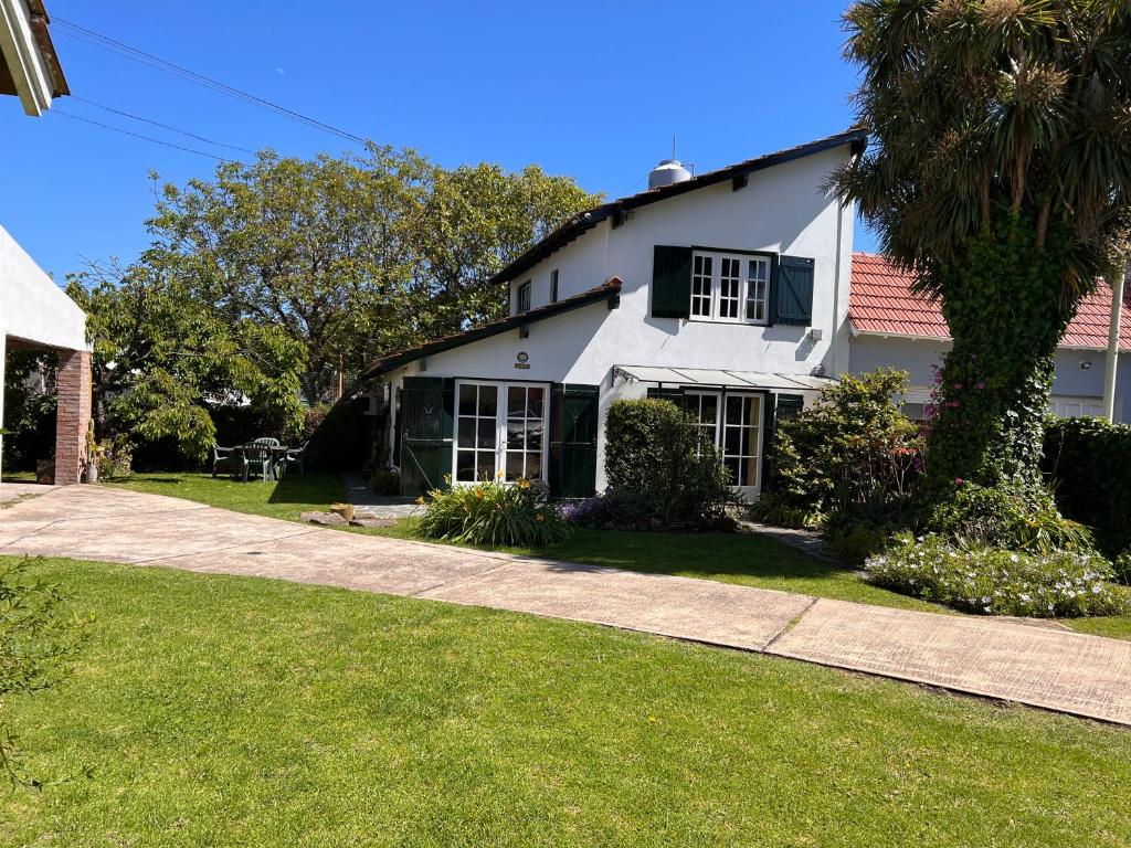ein weißes Haus mit einer Palme neben einem Bürgersteig in der Unterkunft Hermoso Chalet 6 personas a cuadras del Mar in Miramar