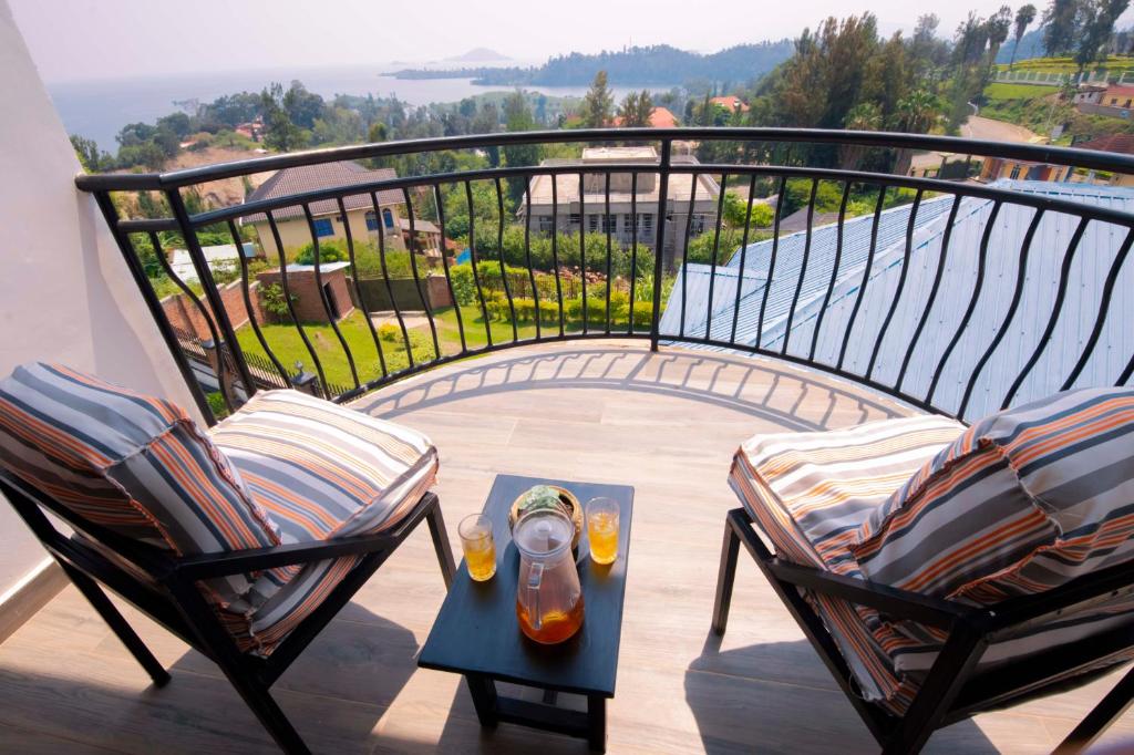a balcony with two chairs and a table with aqual at Elegant Lakeside Villa in Kibuye, Rwanda in Mwendo