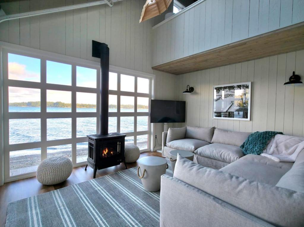 ein Wohnzimmer mit Couch und Kamin in der Unterkunft Beachfront cabin, dock, water views in Point White