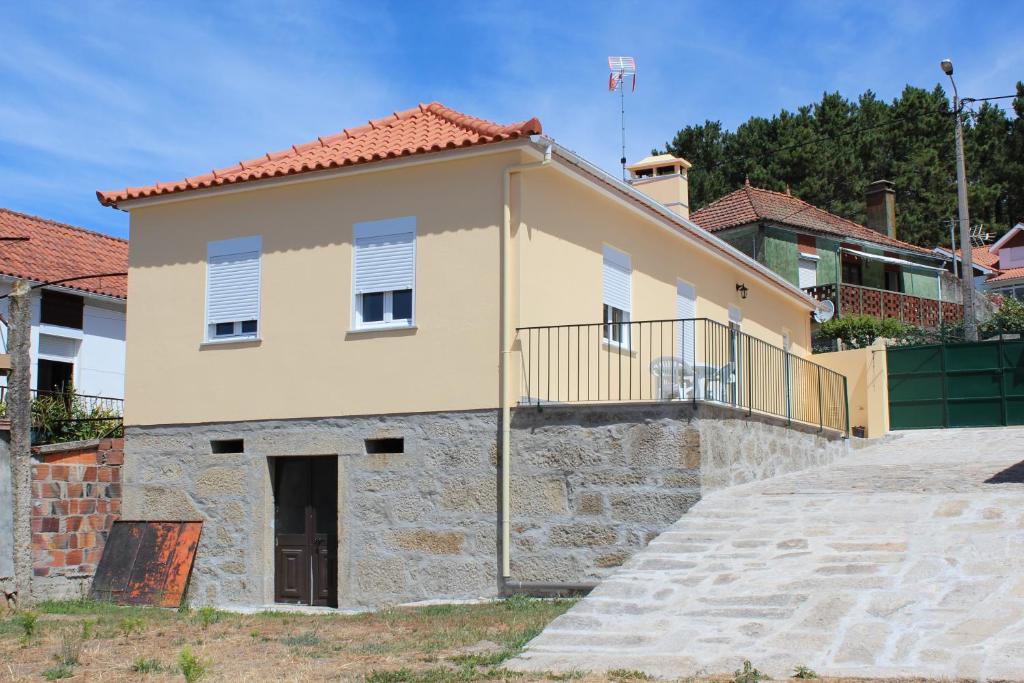 a house with a stone wall and a balcony at A casa do meu Avô in Viana do Castelo