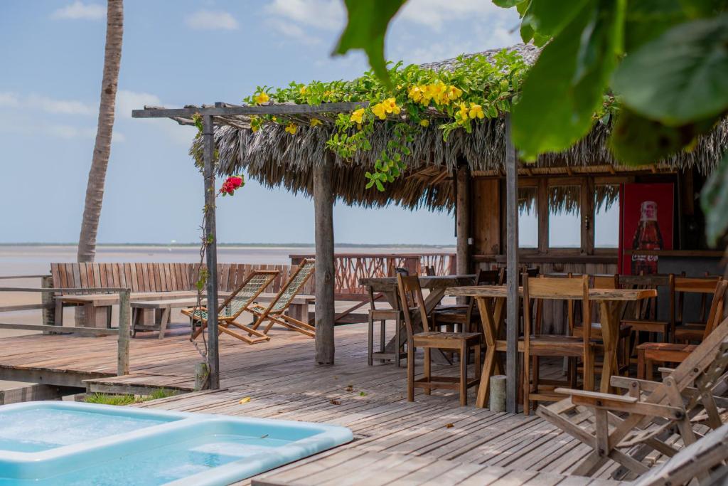 a restaurant with tables and chairs and a swimming pool at Pousada Delta Chalés in Tutóia