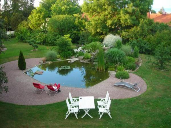 a garden with a table and chairs and a pond at Solrosen i Simrishamn - Österlen in Simrishamn