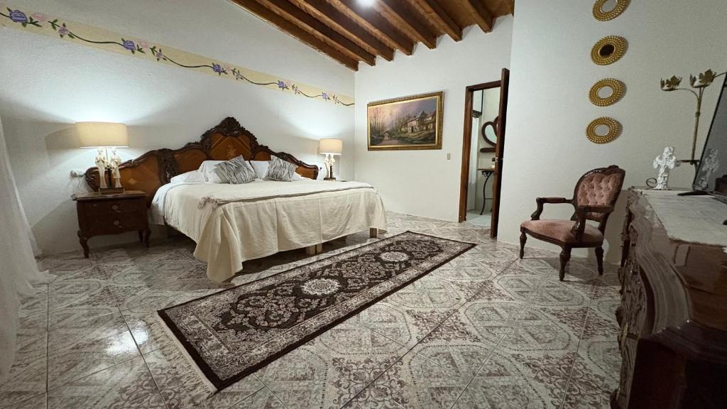 a bedroom with a large bed and a chair at hotel gardenias in Pátzcuaro