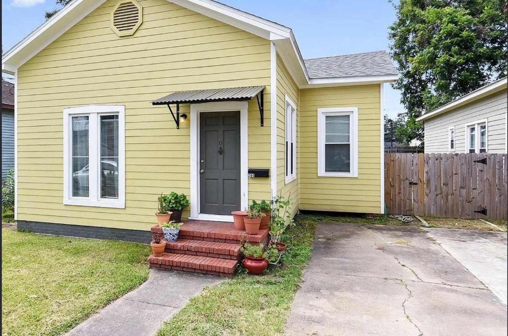 a yellow house with a door and some potted plants at Budget-Friendly Private Room with Homey Feel in Lafayette