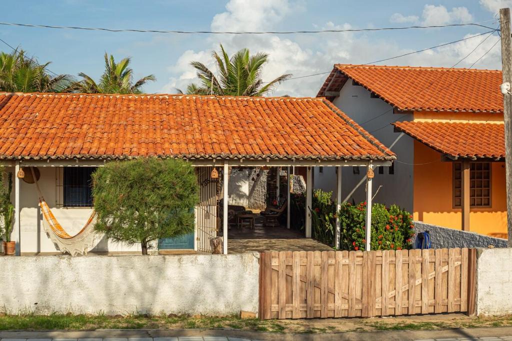 ein Haus mit einem orangefarbenen Dach und einem Zaun in der Unterkunft Chale 19 Praia do BarroPreto in Luis Correia