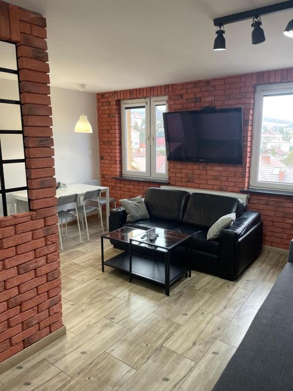 a living room with a black couch and a brick wall at Apartament w centrum in Rymanów-Zdrój