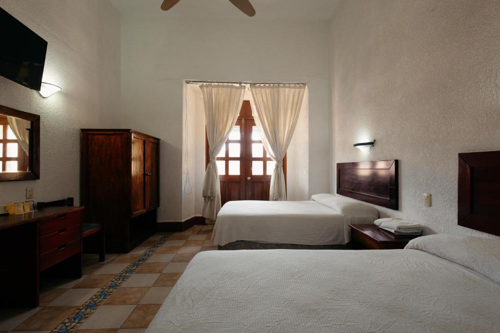 a hotel room with two beds and a window at Hotel Nueva Antequera in Oaxaca City