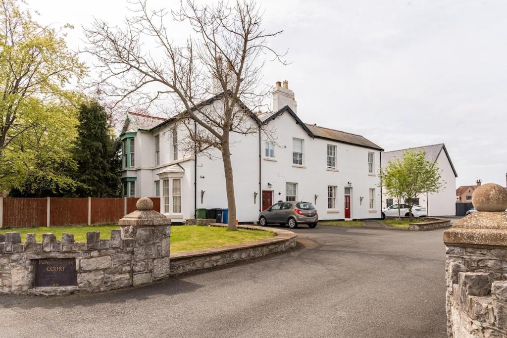a white house with a car parked in the driveway at A former school converted into a luxury apartment in Rhyl
