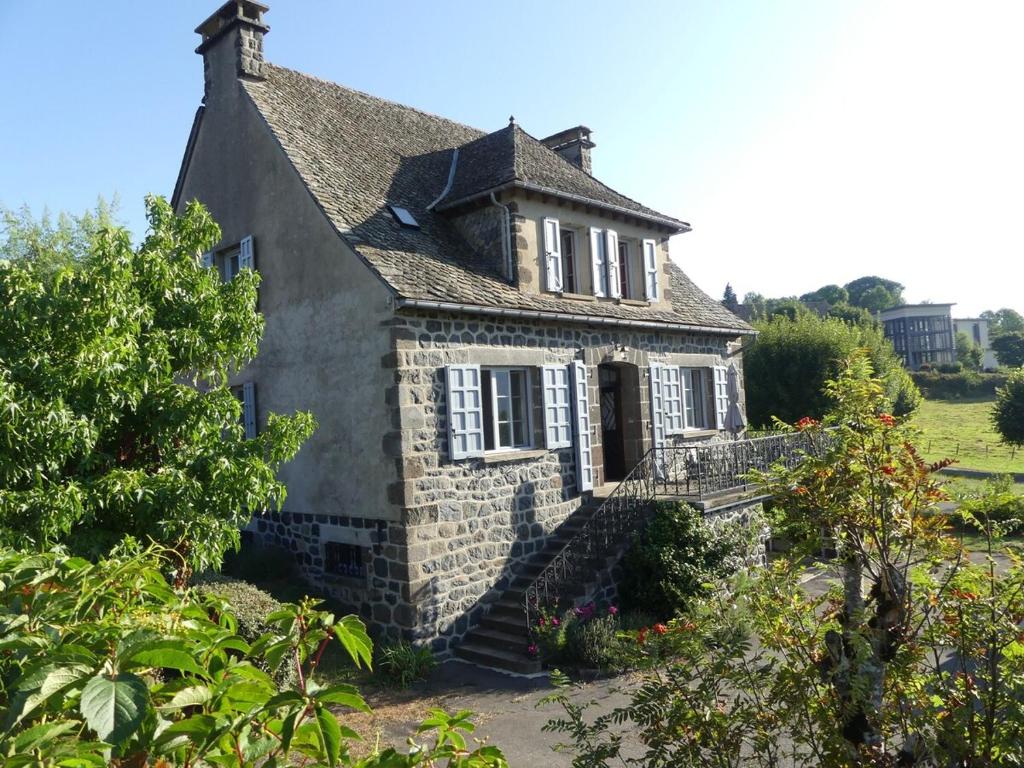 an old stone house with stairs in a garden at L'Oustal de Salers in Salers