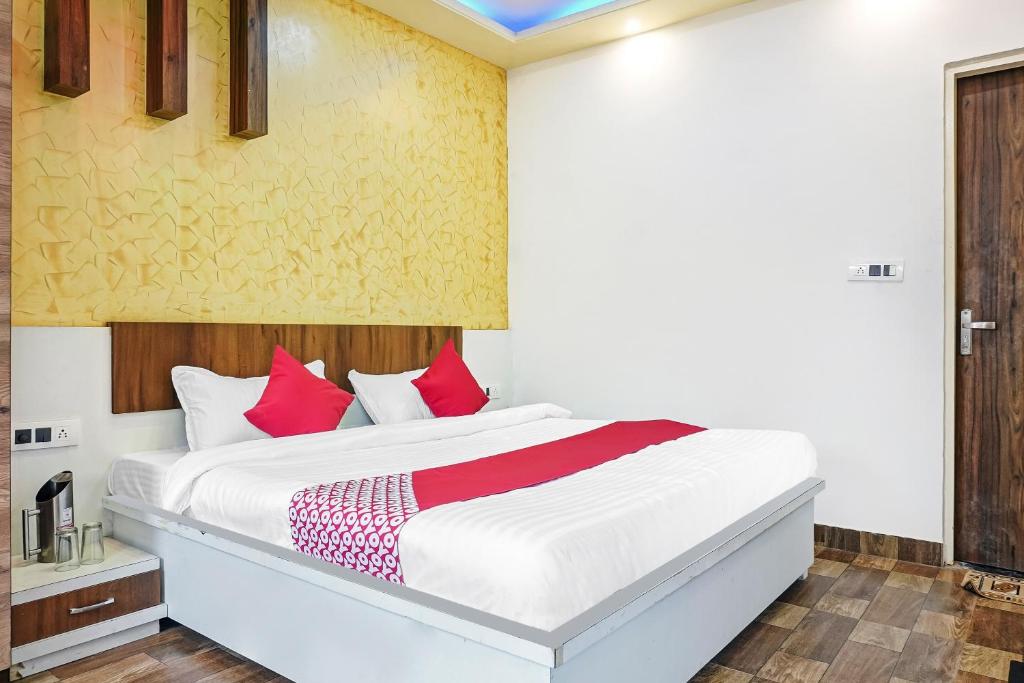 a bedroom with a white bed with red pillows at Hotel O CeeRock in Bhopal