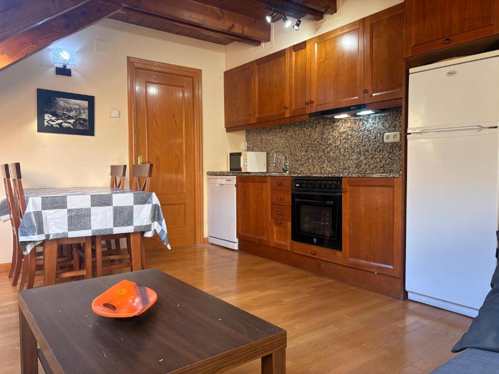 Una cocina con una mesa y un refrigerador blanco. en Cocina moderna, bajo cubierta rústico- Comodidad máxima - Erta 3, en Pla de l'Ermita