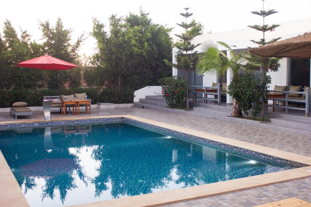 a swimming pool with a table and chairs and an umbrella at Dar naima in Al Ghar