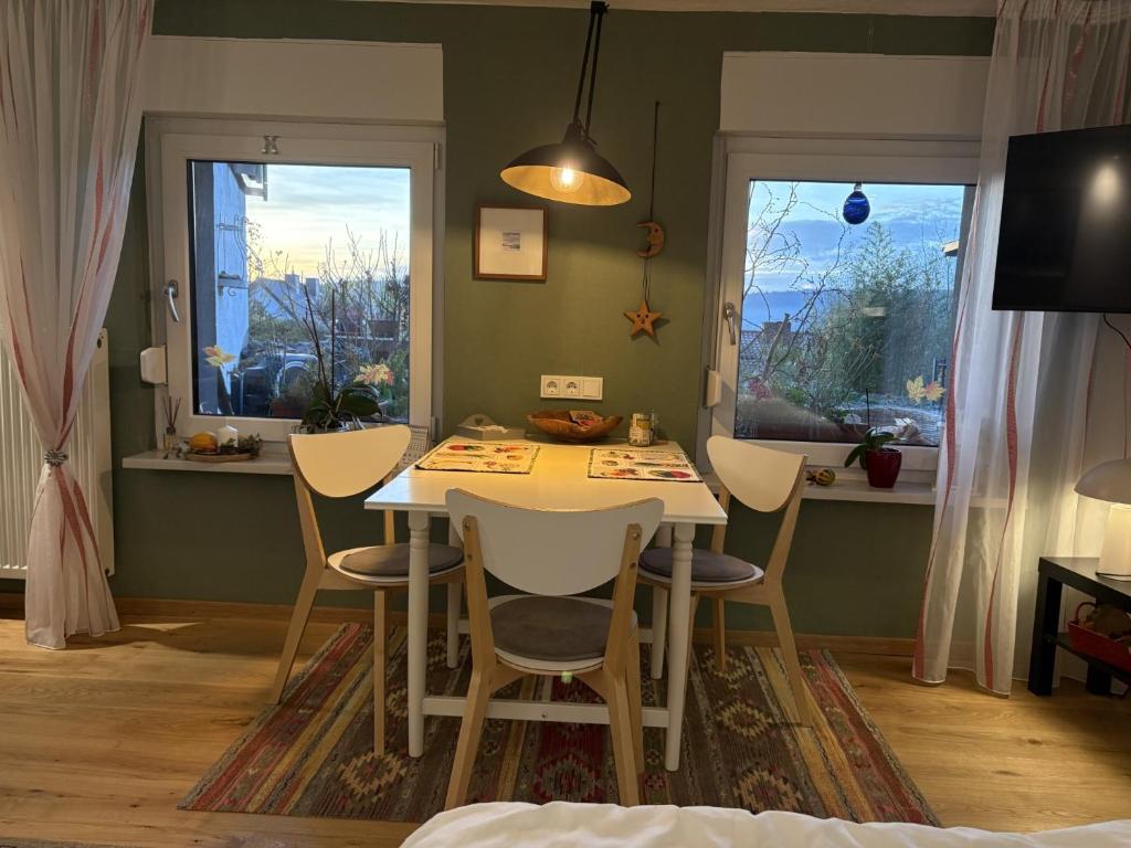 a dining room with a table and chairs and two windows at Ferienwohnung Lahntalblick in Weilburg