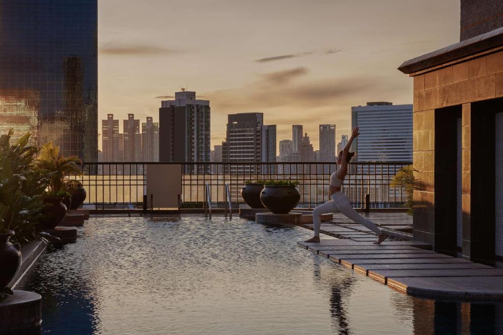 A rooftop pool deck used for yoga against a city skyline.