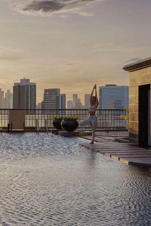 A rooftop pool beside a deck with a city skyline beyond.