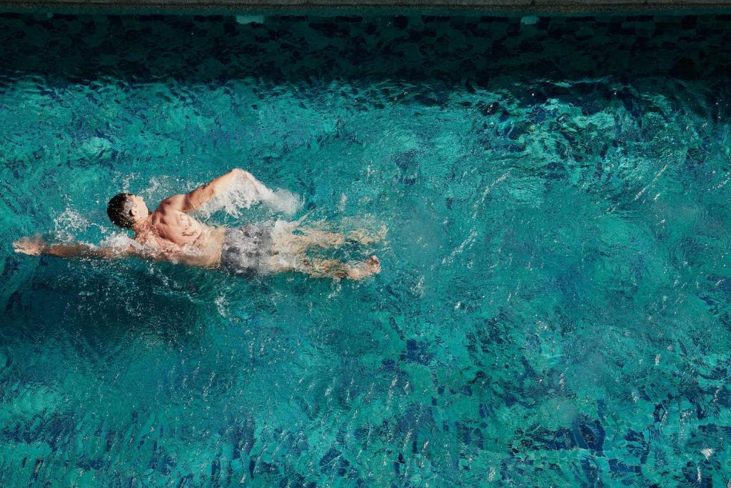 A swimmer crossing a broad turquoise pool.