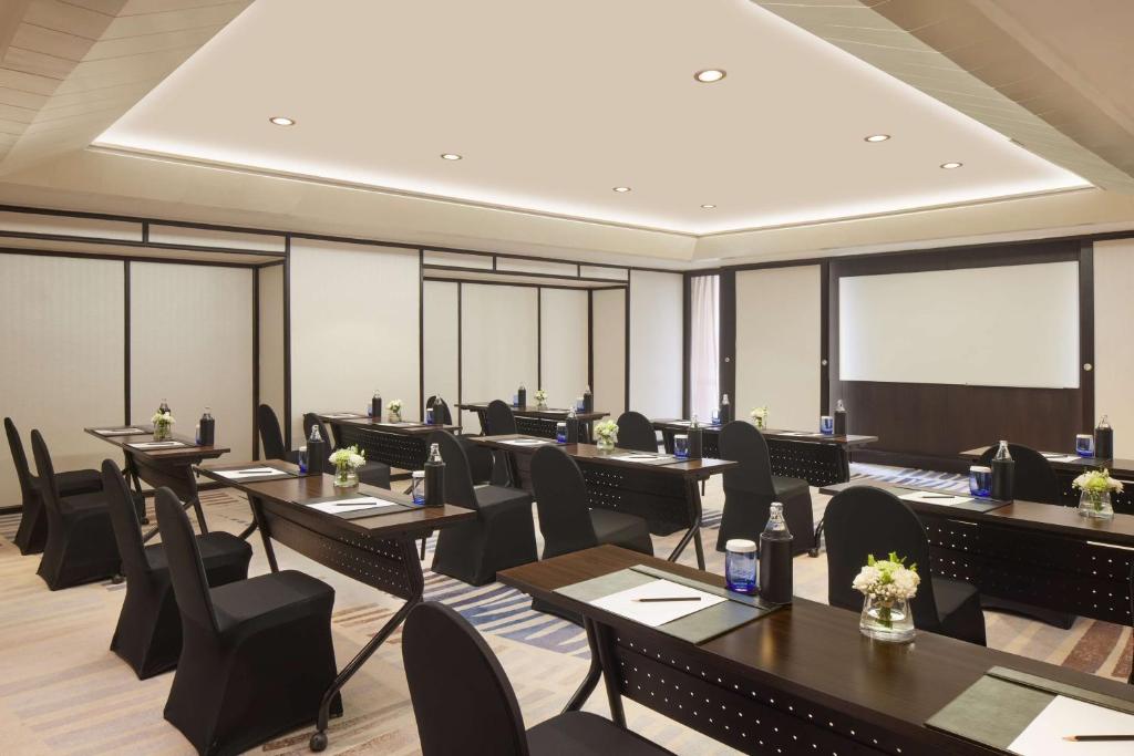 A large conference room is arranged classroom-style with a projection screen.