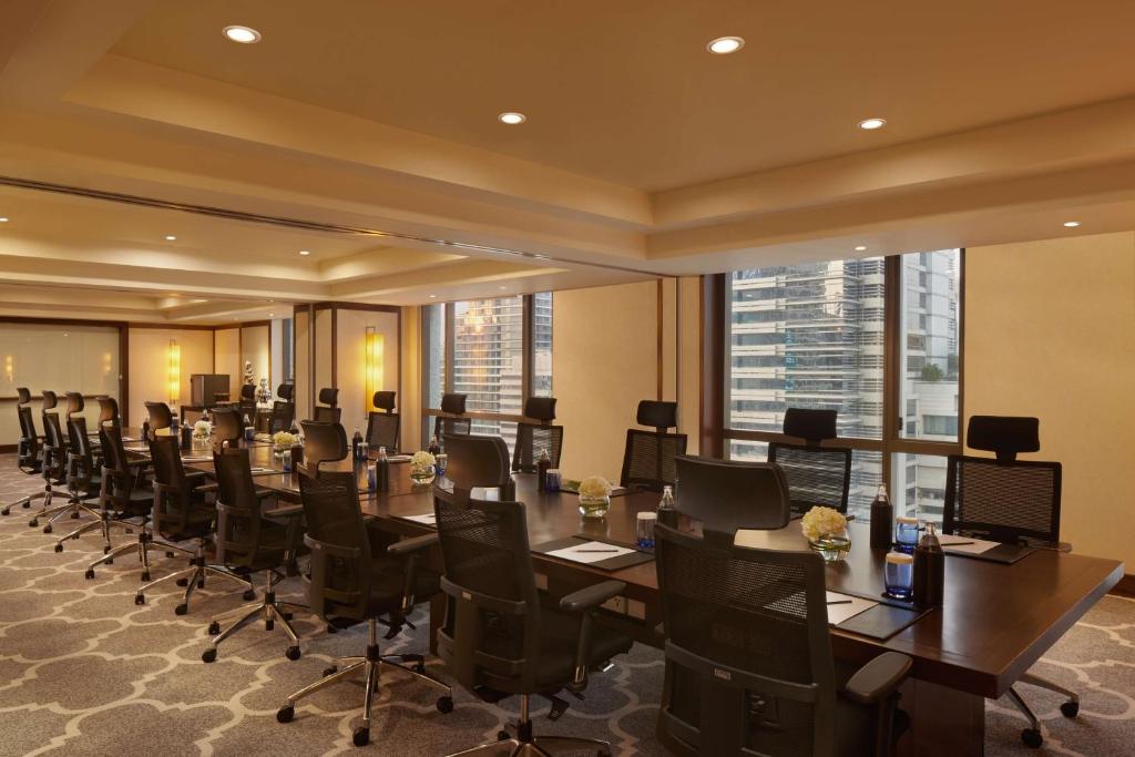 A bright conference room set up with rows of office chairs around a long table.