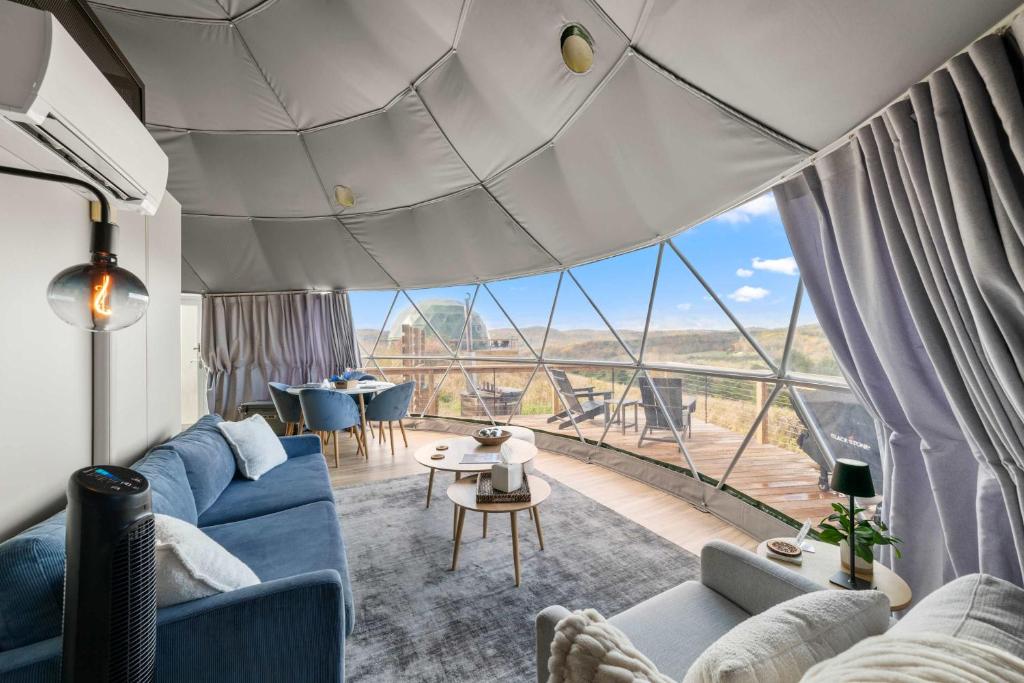 a living room with a blue couch and a large window at Barrel Hot Tub at 'The Eagle Dome' in Franklin in Franklin