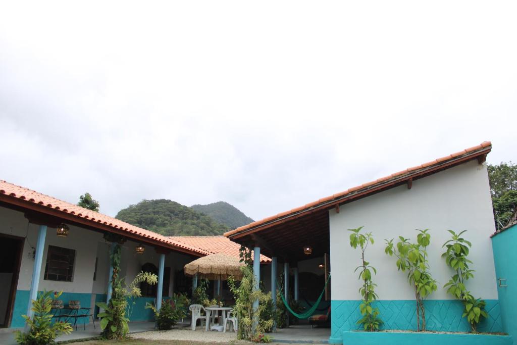 une maison bleue et blanche avec des montagnes en arrière-plan dans l'établissement Azular Ubatuba - Eco Vila, Casas, Bangalôs, Yoga & Surf Inn, à Ubatuba