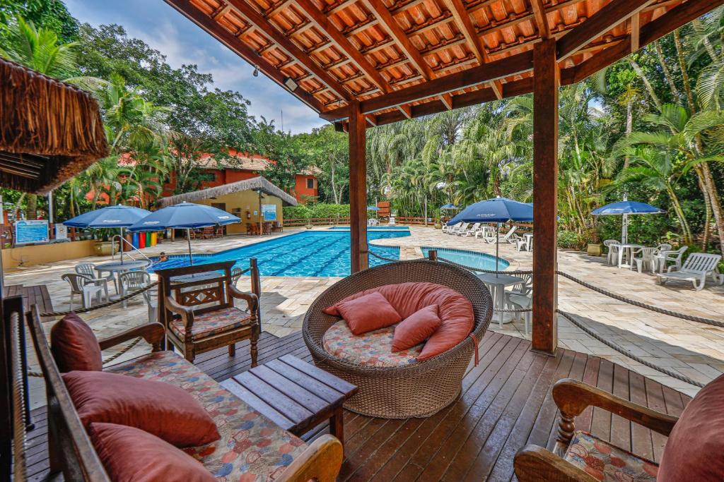 an outdoor patio with a swimming pool and a resort at Flat estudio 110 Amarilis Riviera de São Lourenço, 03 piscina climatizada, serviço de hotelaria, limpesa e troca de toalhas diária, carregador veiculo elétrico e servico de praia finais de semana WiFi 500 in Riviera de São Lourenço