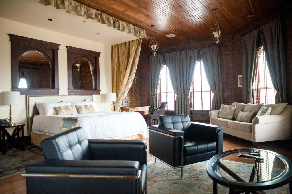 a bedroom with a bed and a couch and chairs at The Hackett Hotel in Marietta