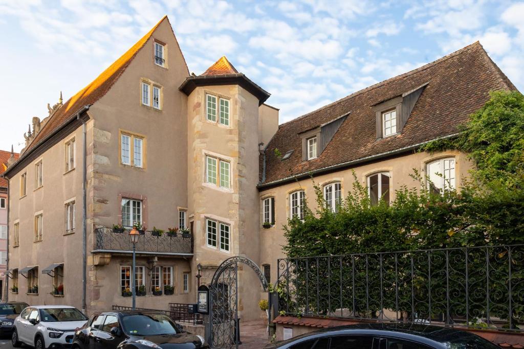 Un edificio con coches aparcados delante. en Hotel Restaurant L'Orchidee, en Ensisheim