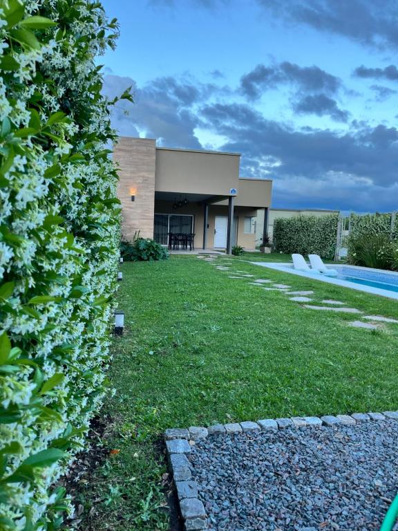 a hedge in front of a house with a yard at Casa Quinta in Chivilcoy