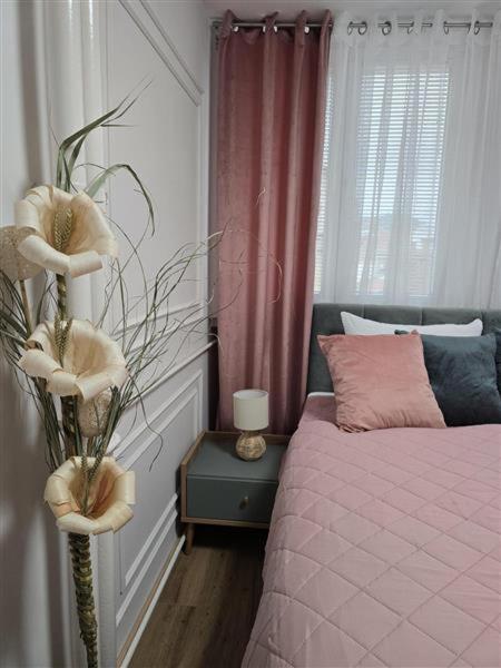 a bedroom with a bed with a pink bedspread at Apartman Karamelica in Užice