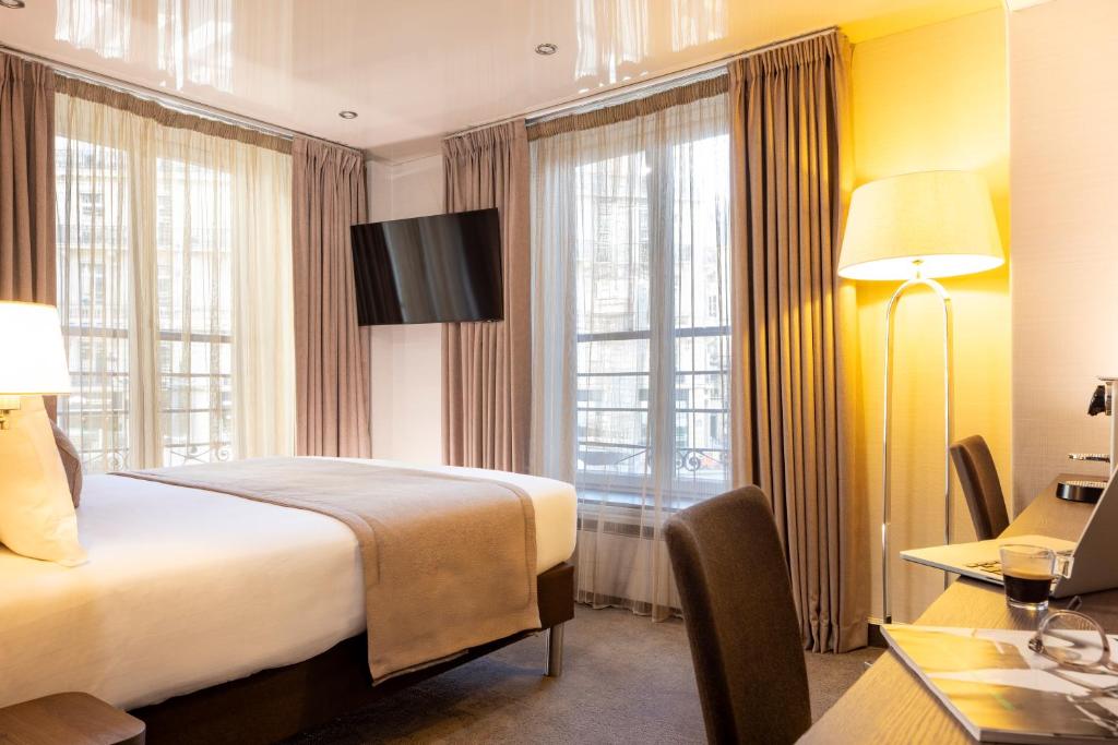 a hotel room with a bed and a desk and window at Hotel Choiseul Opera in Paris
