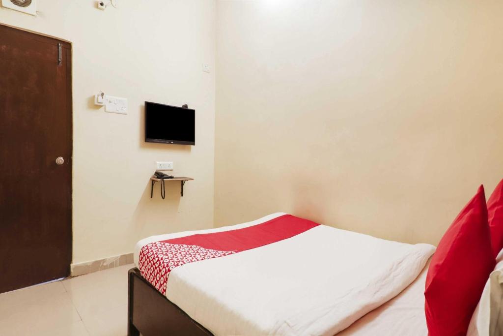 a bedroom with a bed and a tv on the wall at Hotel O Sai Pariwar in Vidya Nagar