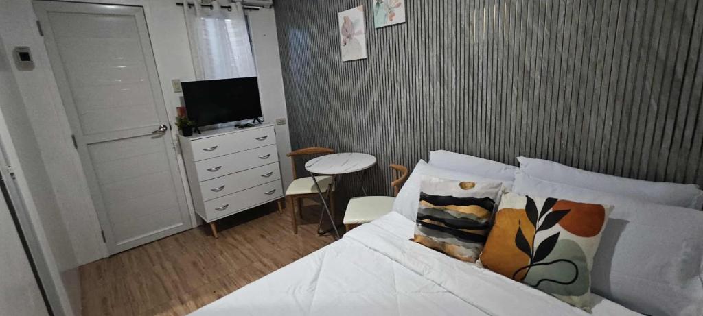 ein Schlafzimmer mit einem Bett und einer Kommode mit einem Fernseher in der Unterkunft Cozy room right in the heart of the city, close to everything you need in Davao City