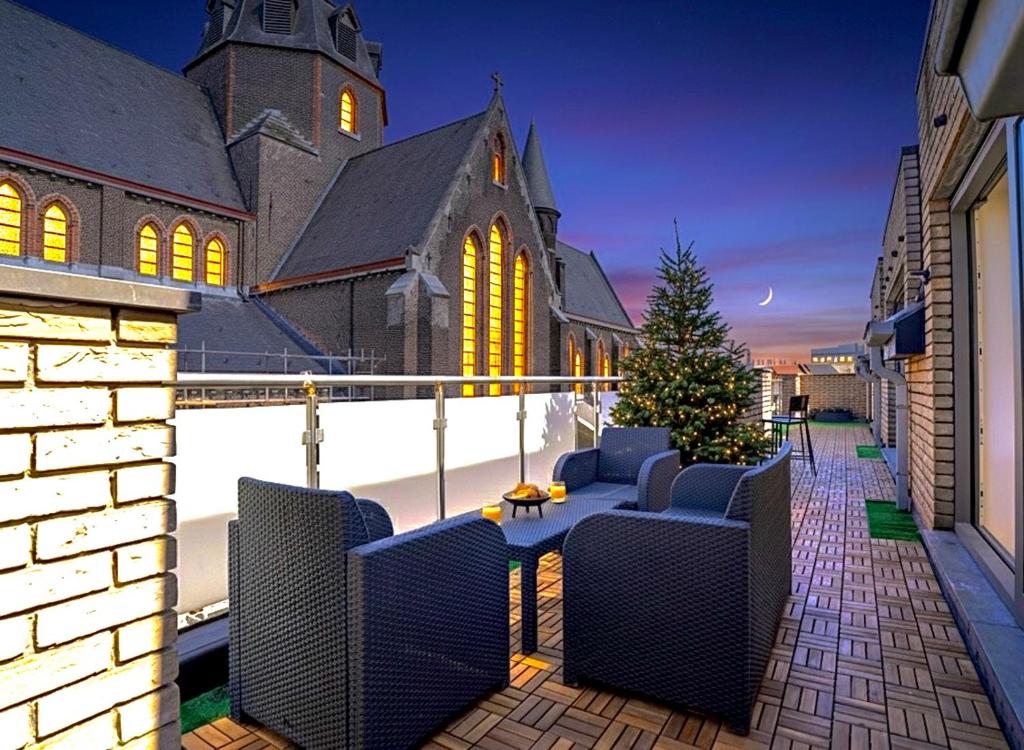 a patio with chairs and a christmas tree in front of a church at Penthouse with a Neo-Gothic Parish church view in Ghent
