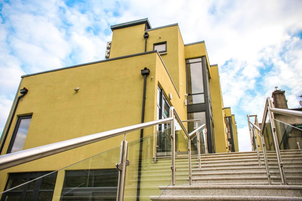 a yellow building with stairs in front of it at Clody Lodge in Bunclody