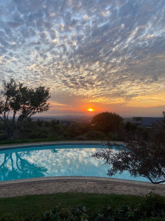 a sunset over a swimming pool with the sun setting at Watermill Ocean View Luxury Family Retreat in Gordonʼs Bay
