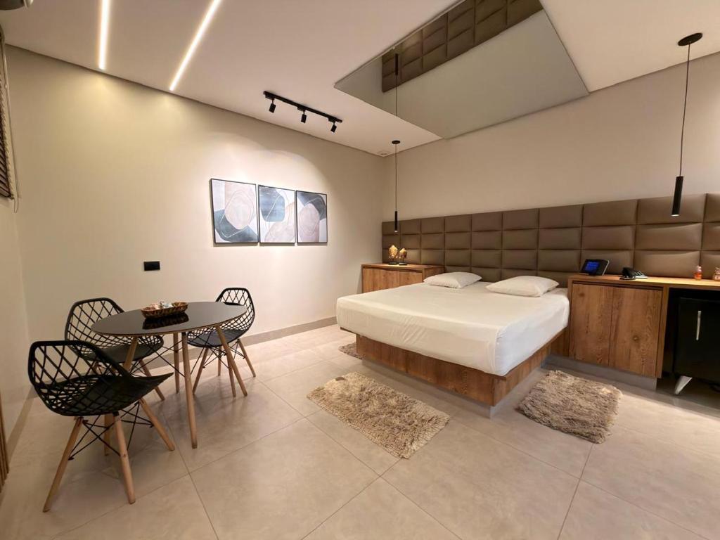 a bedroom with a bed and a table and chairs at Status Motel Ourinhos in Ourinhos