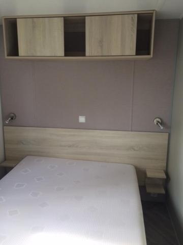 a bedroom with a white bed and a mirror at MOBIL HOME tout confort in Talmont