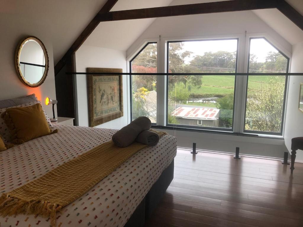 ein Schlafzimmer mit einem Bett und einem großen Fenster in der Unterkunft The FatPonyLodge in Hepburn Springs