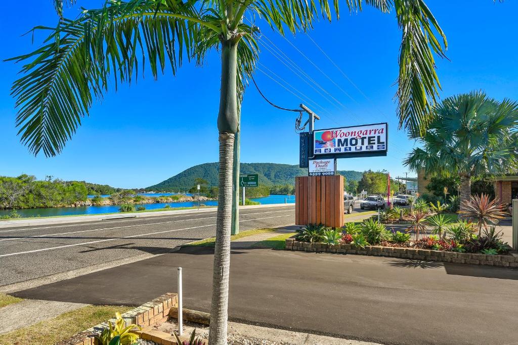 a palm tree next to a street with a motel sign at Woongarra Motel in North Haven