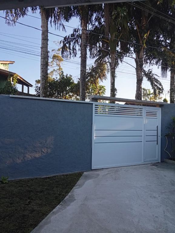 Ein weißer Zaun mit einem Tor im Hof. in der Unterkunft Recanto Amora in Boicucanga