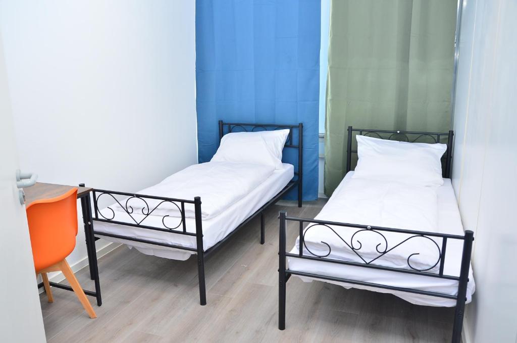 two beds in a room with a table and a chair at Xenon hostels in Dreieich