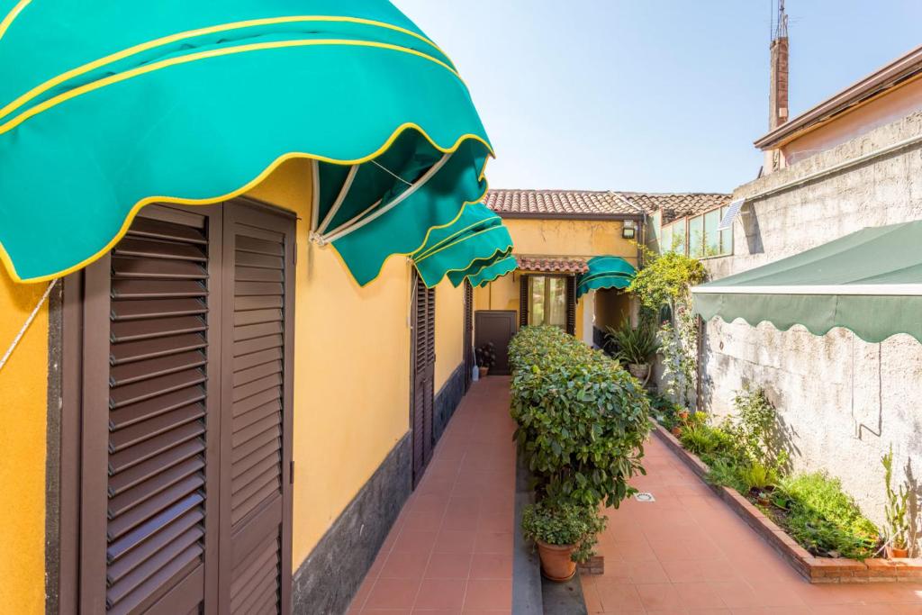 a yellow building with a green awning and a sidewalk at Casa Vacanze vicino Etna - Natura dell'Etna in Belpasso