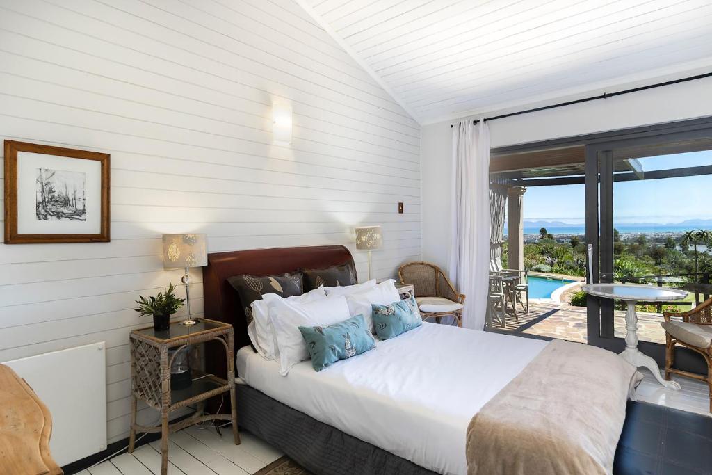 a bedroom with a bed and a balcony with a view at Watermill Studios in Gordonʼs Bay