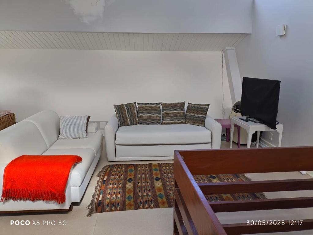 un salon avec un canapé et une télévision dans l'établissement Condo frente mar, à Barra do Una