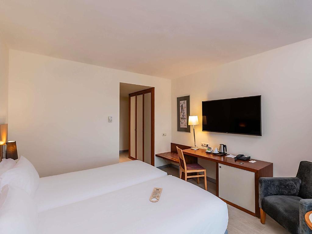 a hotel room with a bed and a desk and a tv at Hotel Mercure Lisboa in Lisbon