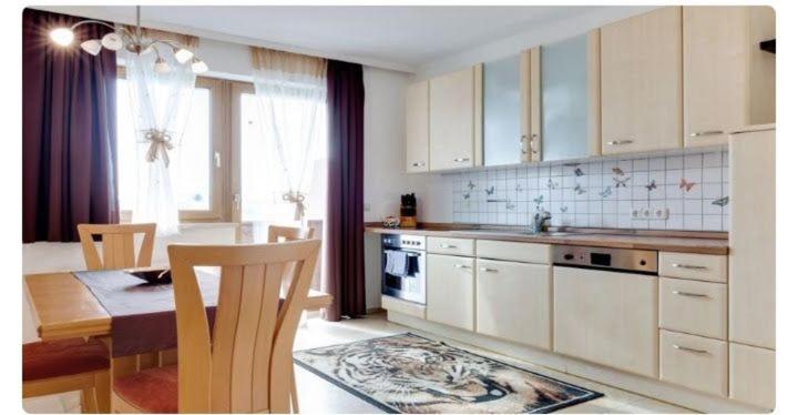 cocina con armarios blancos, mesa y comedor en Ferienwohnung In Ulrichsberg, en Ulrichsberg