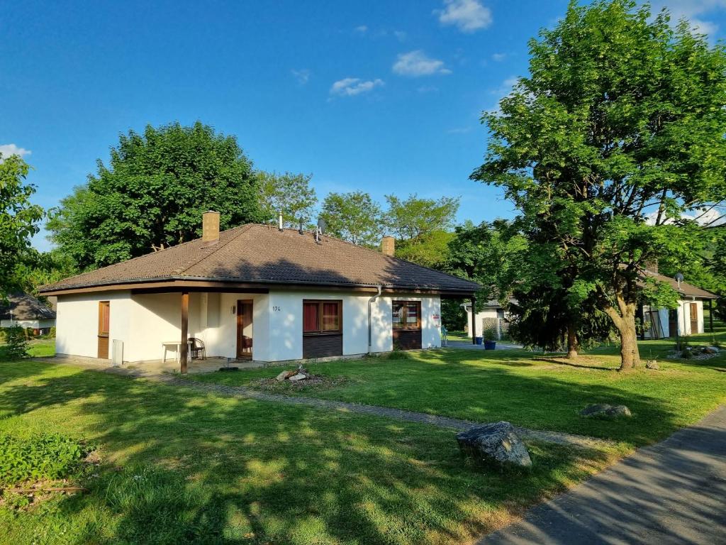 a white house with a tree and a yard at Aurora Lodge in Frielendorf