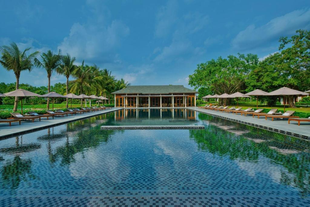 a pool at a resort with chairs and umbrellas at Legacy Mekong, Can Tho, Autograph Collection in Can Tho