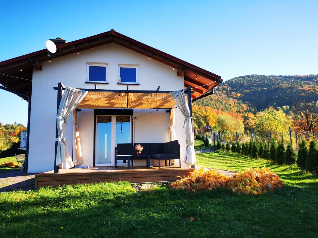 a small white house with a bench in the yard at JAWORNICA HOUSE domek z pięknym widokiem in Targanice